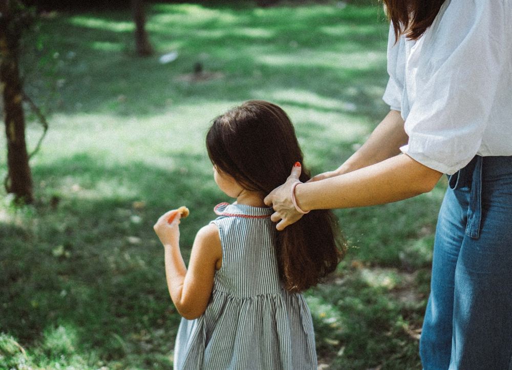 子どもの髪に手を添える保護者と子どもの後ろ姿